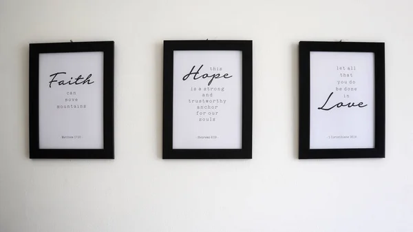Religious texts in photo frames on the wall about faith, hope and love and principles of life based on Bible verses.