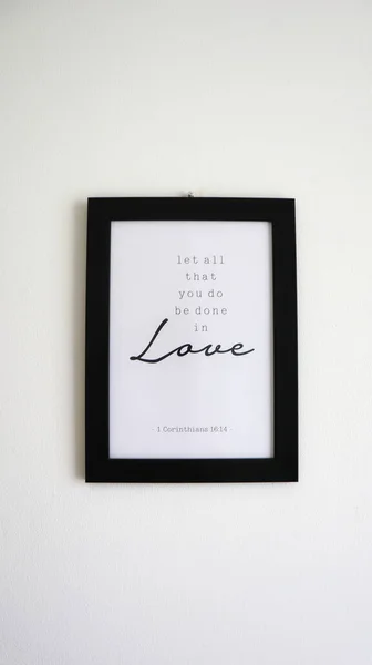 A photo of a frame that reads a bible verse in 1 Corinthians 16:14 about let all that you be done in love.