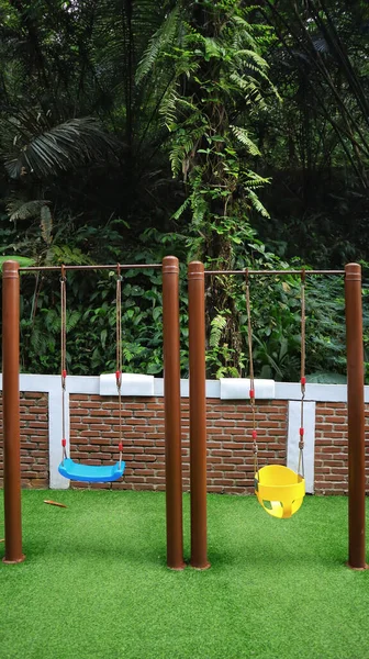 safe and simple children\'s swing in the playground at the backyard with a nature background