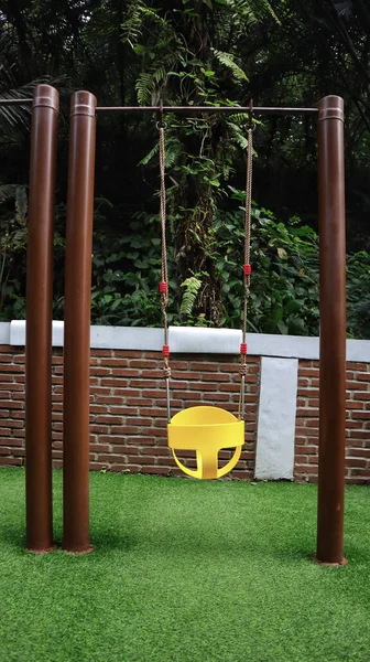 safe and simple children\'s swing in the playground at the backyard with a nature background