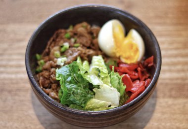 Biftek Donburi Japon pilavı, üzerinde yakiniku bifteği ve yumurta servis edilir..