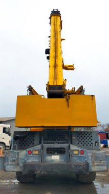 Rear view of yellow mobile crane boom up.