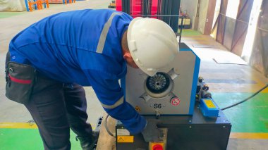 A man operate electrical hydraulic hose press or crimp machine.