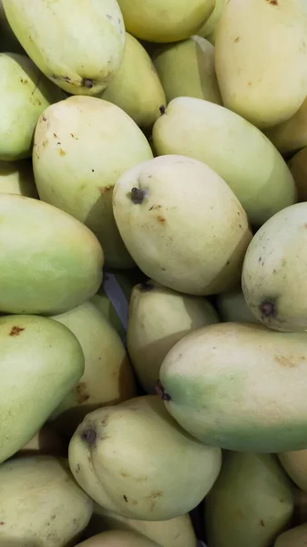 Pile of green mangoes at the market for sale.