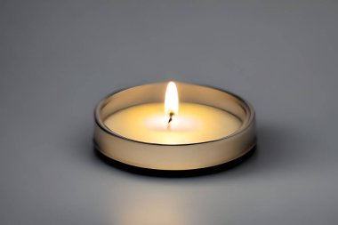 An isolated candle in a glass plate on grey background. Aromatherapy candle.