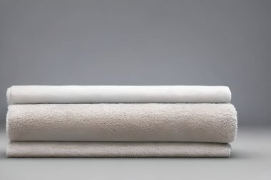 Clean various size white folded towel nice and tidy stack each other for fitness, bath, swimming, massage and spa marketing background and design material isolated on grey background.