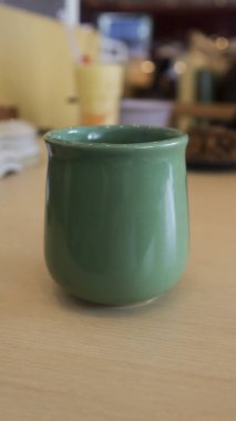 Close up a green ceramic or porcelain mug with tea in it at the table