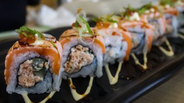 Somon Oyako Baharatlı rulo, çıtır somon derisinden oluşuyor. Suşi pilavı ile sarılmış, yarısı ızgara Aburi Somonu ile baharatlı sos ile kaplı.