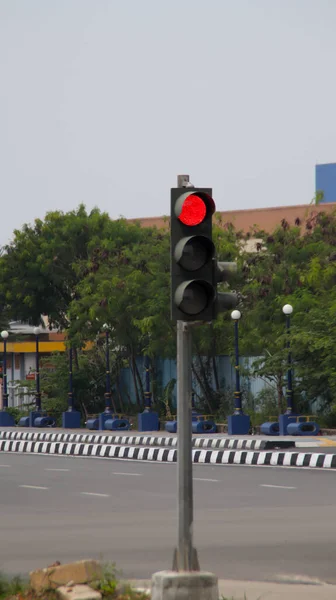 Red traffic light at the road intersection.