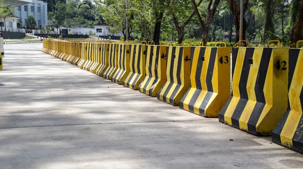 Temporary concrete barrier road divider in yellow and black colors.