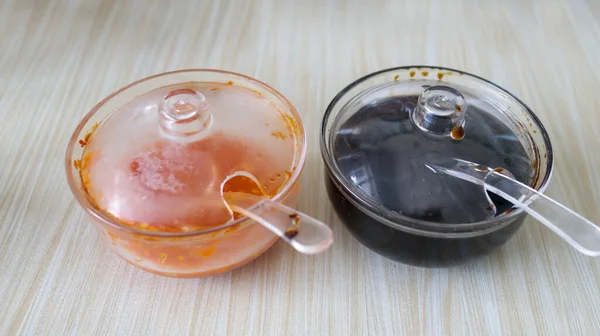 A soy sauce and sweet chili sauce in plastic bowl commonly found in Asian restaurant.