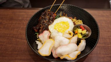 Bir tabak kızarmış erişte, karides kraker, tavuk satay, sahanda yumurta ve biraz turşu..