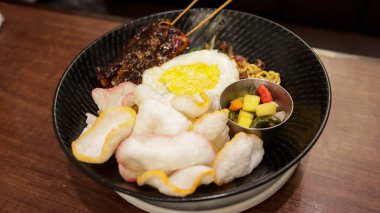 Bir tabak kızarmış erişte, karides kraker, tavuk satay, sahanda yumurta ve biraz turşu..