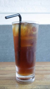 Masanın üzerinde pipetle uzun bir bardak buzlu çay..