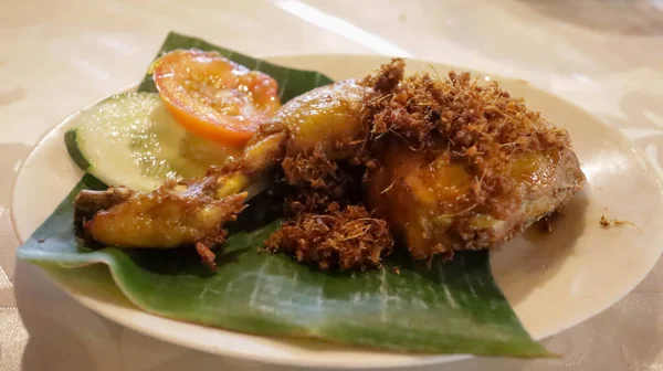 チキンセルデンまたはフライドココナッツフレークとフライドチキン いくつかのキュウリとトマトスライスはプレートでバナナの葉の上に役立ちました インドネシア料理 — ストック写真