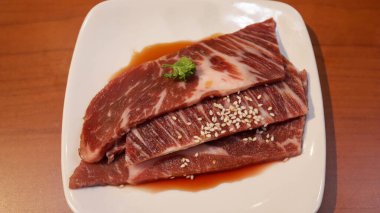 Izgara ya da barbekü için beyaz tabakta tereyağlı soya soslu taze biftek ya da domuz eti. Japon Wagyu bifteği..