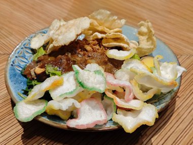 Traditional Indonesian Gado Gado with Peanut Sauce, fish crisp and Emping Melinjo on Wooden Table clipart