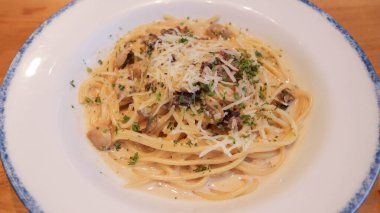 Mantarlı kremalı Carbonara Spagettisi ve beyaz tabakta otlar.