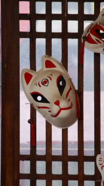 Geleneksel Japon Kitsune Maskesi, Kültürel Ayarlarda Kırmızı ve Beyaz Tasarım Elementlerinin yer aldığı, Işık Süzgeçli Ahşap Ağaca Asılı