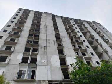 Şehir Bölgesi 'nde terk edilmiş yüksek binalar, Bulutlu Gökyüzü Altında Beton Cephe, Şehir Çürümesini Yansıtan