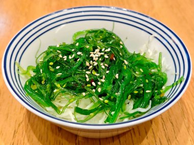 Parlak Yeşil Wakame Salatası Mavi ve Beyaz kâse Tahta Masa üzerinde Susam tohumlu