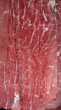 Kırmızı renkte mermer kesilmiş et dilimleri. Detaylı doku ve mermerden arkaplanı temiz bir kasap dükkanında sergilenmek üzere düzgünce düzenlenmiş.