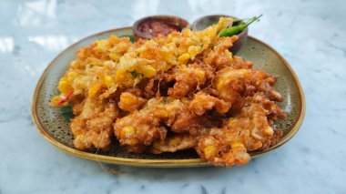 Altın Kahverengi Bakwan Jagung ya da Endonezya Mısır Böreği, acılı sos ve mermer tabakta taze yeşil biber.