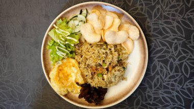 Lezzetli kızarmış pilav ızgara tavuk ve taze sebzeli salata üzerine kahverengi tabakta karides kraker ve masa örtüsü.