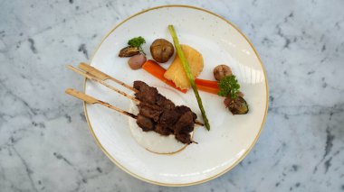 Enfes kaplamalı Dendendeng Çağı ızgarasında tuzlu soslu sebze ve mermer masa üstü Tuber Garnitürü.