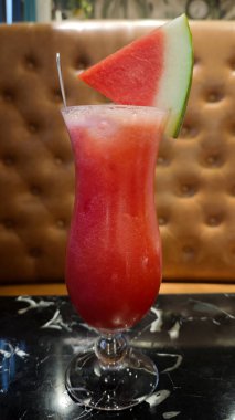 Kavisli Kadehte Karpuz Suyu 'nu Deri Yastıklı Mermer Masa üzerinde Garnitür Karpuz Dilimi ile Taze Karpuz Dilimi