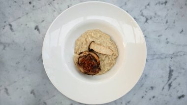 Güzel bir akşam yemeğinde mantarlı ve kremalı tavuklu risotto tabağı mermer masada.