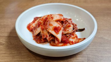 Close-up of Traditional Korean Kimchi in a White Ceramic Bowl on Wooden Table clipart