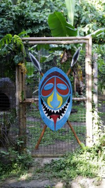 Parlak Renkli Kabile Kalkanı ve mızrak süslemesi Kalın Yeşil Bahçe 'de bir tel örgüye yerleştirilmiş