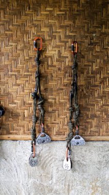 Outdoor climbing equipment with carabiners and rope hanging on bamboo wall in a rustic setting showcasing adventure tools and safety gear clipart