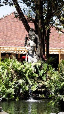 Serene Garden 'da Yeşillik ve Akan Su ile Bali Taş Heykeli