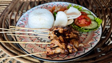 Geleneksel Endonezya Pilavlı Satay Tabağı, Taze Sebzeler, ve Fıstık Sosu Rattan Masası Dekoratif Tabağı Üzerinde Canlı Renkler