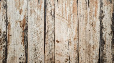 Yıpranmış ahşap döşemeler, doğal kahverengi ve bej tonlarda, eski bir dış mekanda görünen tahıl düğümleri ve pürüzlerle dikey ahşap bir yüzey oluşturuyor.