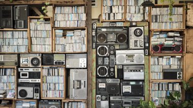 Ahşap sandıklar, yeşil bitkiler ve nostaljik bir atmosferle dolu eski kaset kasetlerle dolu antika ahşap raf ve rustik bir ortamda retro müzik kutuları..