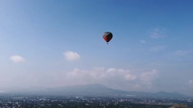 Meksika 'daki Teotihuacan Piramitleri üzerinde güneşin doğuşunu gösteren sıcak hava balonu manzarası.