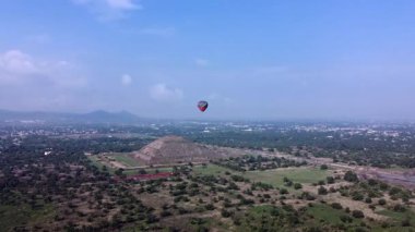 Meksika 'daki Teotihuacan Piramitleri üzerinde güneşin doğuşunu gösteren sıcak hava balonu manzarası.
