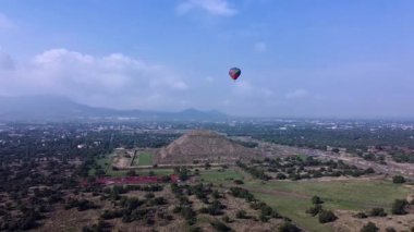 Meksika 'daki Teotihuacan Piramitleri üzerinde güneşin doğuşunu gösteren sıcak hava balonu manzarası.