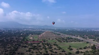 Meksika 'daki Teotihuacan Piramitleri üzerinde güneşin doğuşunu gösteren sıcak hava balonu manzarası.
