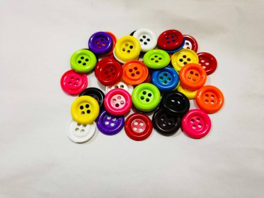 plastic colored buttons on the white background. red, orange, purple blue, black, and green