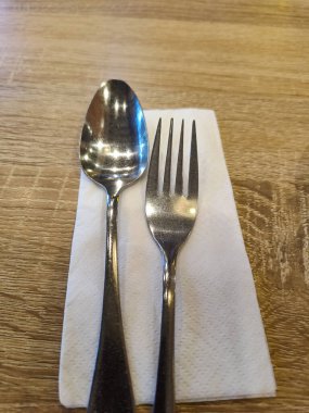 Silverware spoon and fork set with white tissue paper on the table.
