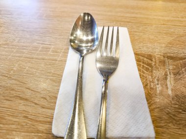 Silverware spoon and fork set with white tissue paper on the table.