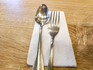 Silverware spoon and fork set with white tissue paper on the table.