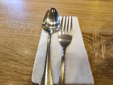 Silverware spoon and fork set with white tissue paper on the table.