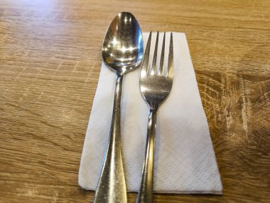 Silverware spoon and fork set with white tissue paper on the table.