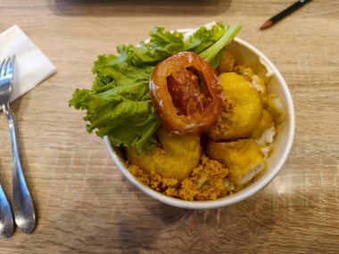 A cup of rice and fried prawn with eggs and vegetables in a restaurant
