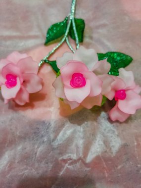 Artificial plastic flower on the shiny pink background